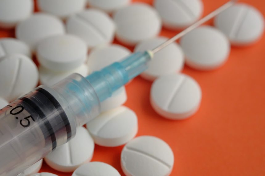White medical pills and tablet on Orange background